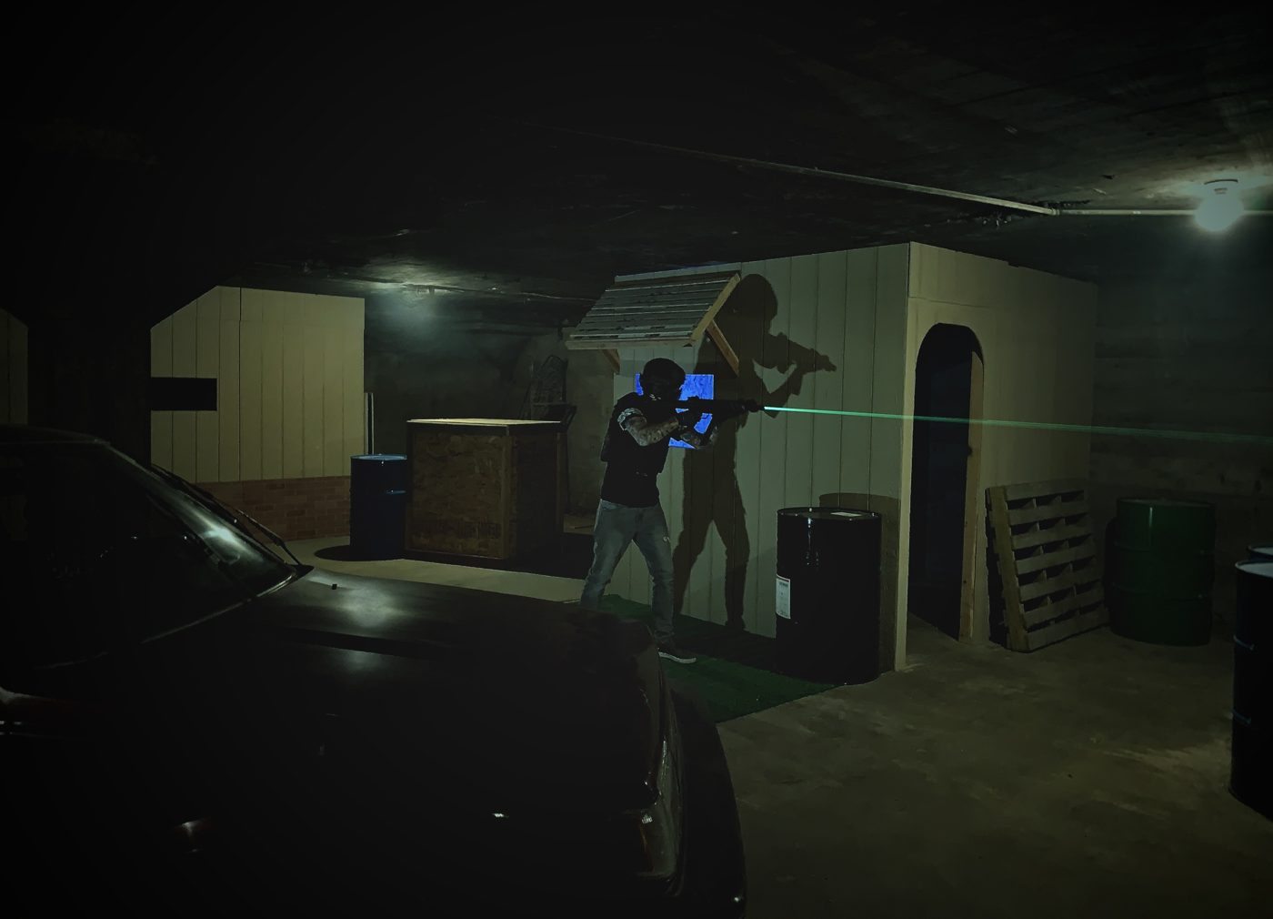 A player with a green laser sight moving through the dark arena