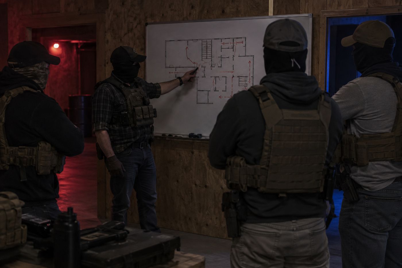 An instructor briefing a team at a whiteboard floor plan